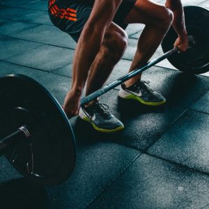 A person lifting a barbell in a gym, symbolizing the flexibility and adaptability of a traveling personal trainer working in various locations.