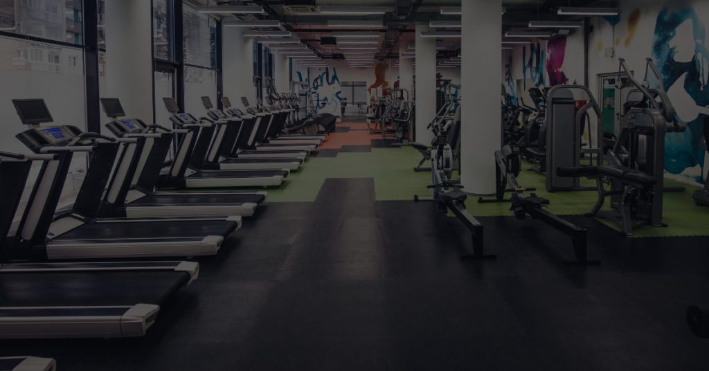 An empty, modern gym with rows of treadmills and strength equipment, symbolizing the strategies needed to retain personal training clients and build a loyal customer base.