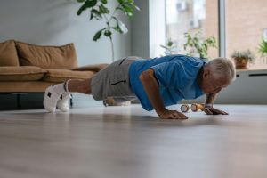 An active senior man performing push-ups on the floor in a bright living room, showcasing strength training at home.