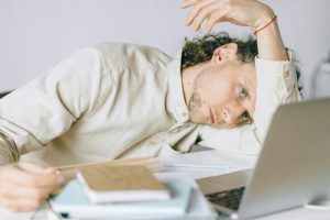 man tired and leaning over desk