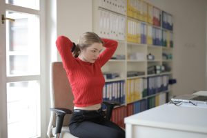 woman in chair stretching at desk