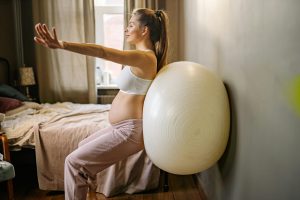 pregnant woman trying ball stretches on wall