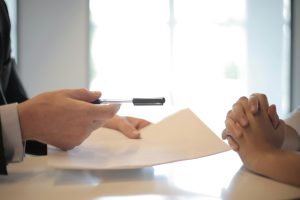 handing pen to sign paperwork