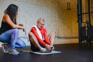 personal trainer monitors client stretching in butterfly position