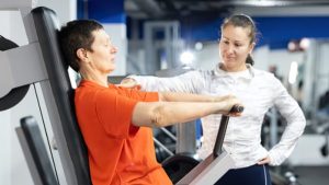 personal training guiding client through safe machine exercise for nerve damage relief