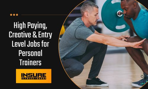 A personal trainer is coaching a client through a barbell squat at the gym. The trainer, wearing a gray shirt and black pants, is crouched down, providing guidance and support with his hands extended. The client, dressed in a teal shirt and black shorts, is focused on maintaining proper form while lifting a barbell with green weight plates.